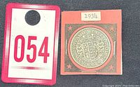 Photo of the coin mounted on a pink and gray card with 1934 label and auction lot number 054.