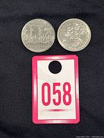 Two Canadian commemorative dollar coins on black background with identification tag