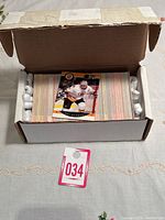 Box of tightly stacked 1990-1991 Pro Set Hockey trading cards shown with some packing foam and a lot tag '034'