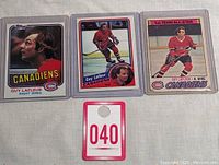 Three vintage Guy Lafleur hockey cards displayed side by side with a numbered tag in front