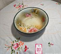 Front and top view of antique Nippon hand painted floral bowl on embroidered tablecloth, showing pink, yellow, and red roses inside.