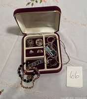 Jewelry assortment displayed in AVON jewelry box with various rings, a necklace, and bracelets.