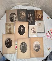 Overview of the 12 antique vintage portraits laid on table, various mounted photographs, showing formal and casual attire