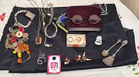 Overall lot on black cloth showing jewelry grouping, spoons, thimble, rings, glasses