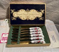 Set of 6 knives inside original box with floral bone china handles and gold-toned blades, green interior padding.