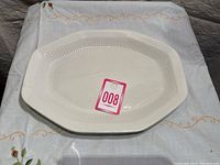Top view of white octagonal serving plate with ribbed finish on inside rim and lot number sticker.