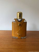 Front view of the glass flask with brown leather cover and gold screw cap, showing embossed CN Tower graphic.