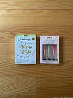 Photo showing unopened boxes of the face mask and lip oil trio on wood floor.