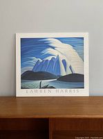 Front view of the plaque displaying the Lawren Harris artwork 'Lake and Mountains' on a wooden surface.