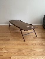 Full angled view of table showing curved side rails and decorative inlay blocks