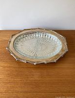 Vintage serving tray with metal frame and glass divided insert shown from above on wood surface.
