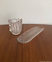 Photo showing vintage glass ice bucket and matching glass tray side by side on wooden surface.