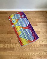 Towel laid flat showing colorful hot air balloon design and overall size on wood floor.