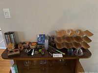 Photo showing full set of barware accessories and the wine rack on a wood table, including ice bucket, coasters, stoppers, corkscrew, and other tools.