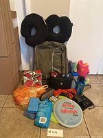 Overview of outdoor gear items including the backpack, binoculars, inflatable pillows, ropes, frisbee, water bottle, and various small accessories arranged on a tiled floor.