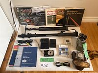 Full shot showing Sony Cyber-shot camera, tripod, binoculars, books, cables, charger, and camera case.