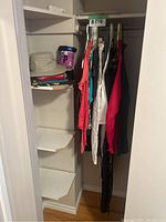 Photo of closet with hanging women's clothing and Tilley hat on shelf