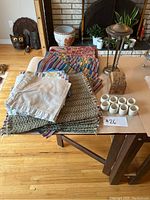 Photo showing the entire lot of linens and incense holder on a table, displaying placemats, napkins, incense holder, and white ceramic cups.