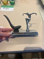 Side view of vintage pipe holder with candle wax residue visible inside pipe rest and figurine attached to base.