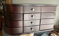 Front view of dark brown wooden jewelry box with 4 rows of drawers, side swing-out drawers and metal knobs