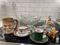 Overview photo of lot showing Pendelfin Sir John Falstaff Toby Mug, Royal Grafton cup and saucer, pressed glass bowl, crystal horse figurine, smaller figurines, and crystal decanter.
