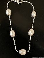 Full view of the fresh water pearl bracelet showing its oval pearls and silver bead accents on a black background.