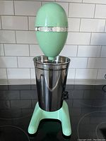 Front view of the retro Hamilton Beach Drink Master mixer with stainless steel cup on a stovetop