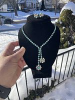 Full view of signed Jayflex sterling silver necklace and matching earrings displayed on black stand outdoors with snow background.