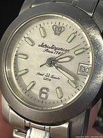Front dial showing luminescent markers, hands, date window, and branding