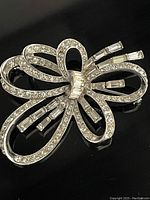 Close-up front view of the silver-tone bow pin with clear round and baguette rhinestones.