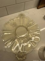 Full view of the yellow depression glass cake plate showing fluted edges, integrated fluer de lis design, and handles.