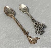 Photo showing two vintage sterling silver collectible spoons, one shaped with a bird handle and one a Florida souvenir spoon.