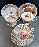 Three vintage Royal Albert teacups with matching saucers, assorted floral and fruit designs, front view showing all pieces.