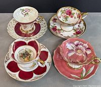 Four vintage Japanese teacups with matching saucers showing floral and classical designs with gold accents
