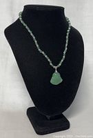 Necklace displayed on black bust showcasing the round green jade and clear crystal beads with the Buddha pendant