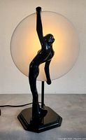 Oblique front view with lamp lit showing silhouette of black figural nude and frosted glass disc.