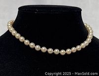 Front view of pearl necklace displayed on a black bust stand, showing uniform pearls around 14-inch length.