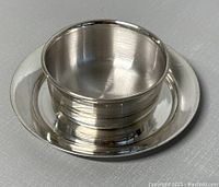 Silver bowl sitting centered on matching plate, showing full top view and polished finish.