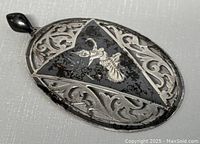 Close-up of pendant front showing the dancer figure in the black enamel triangular center of the oval sterling silver pendant with openwork scroll design.