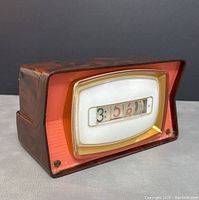 Side angled view showing retro TV shape and rolling number display of vintage clock.