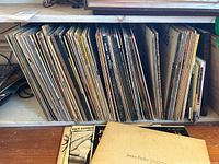 Shelf with vinyl record albums tightly packed showing spines with artist and composer names.