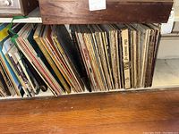 Wide view of vinyl albums lined up on shelf showing variety of album spines including 'The Music of Life'