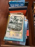 Top view of a box filled with architecture-related books with visible titles including Remodeling Old Houses, Architectural Graphic Standards, and Bringing Down the House.
