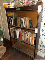Front view of three shelf barrister bookcase filled with books on middle and top shelves, bottom shelf empty, showing wood finish and condition.