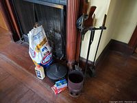 Wide view of fireplace with tool set, screen, kettle, charcoal and starters arranged on hearth