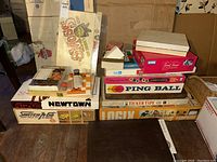 Stack of vintage board games showing original boxes including Switch and Go, Newtown, Ping Ball, Ticker Tape and others.