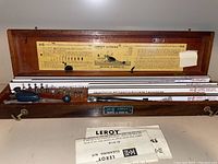 Closed wooden case with Leroy lettering instructions on the inside of the lid, showing contents of lettering templates and tools inside.