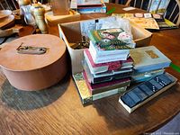 Full view of poker chip carousel case, stacked playing card decks, boxed dominoes, and chess pieces in bag on wooden table