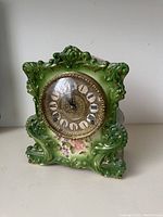 Full view of green ornate Gilbert porcelain clock with gold accents and floral motif