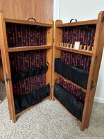 Open view of antique wooden sewing spool case showing interior fabric lining, pockets, and wooden dowels with thread spools.